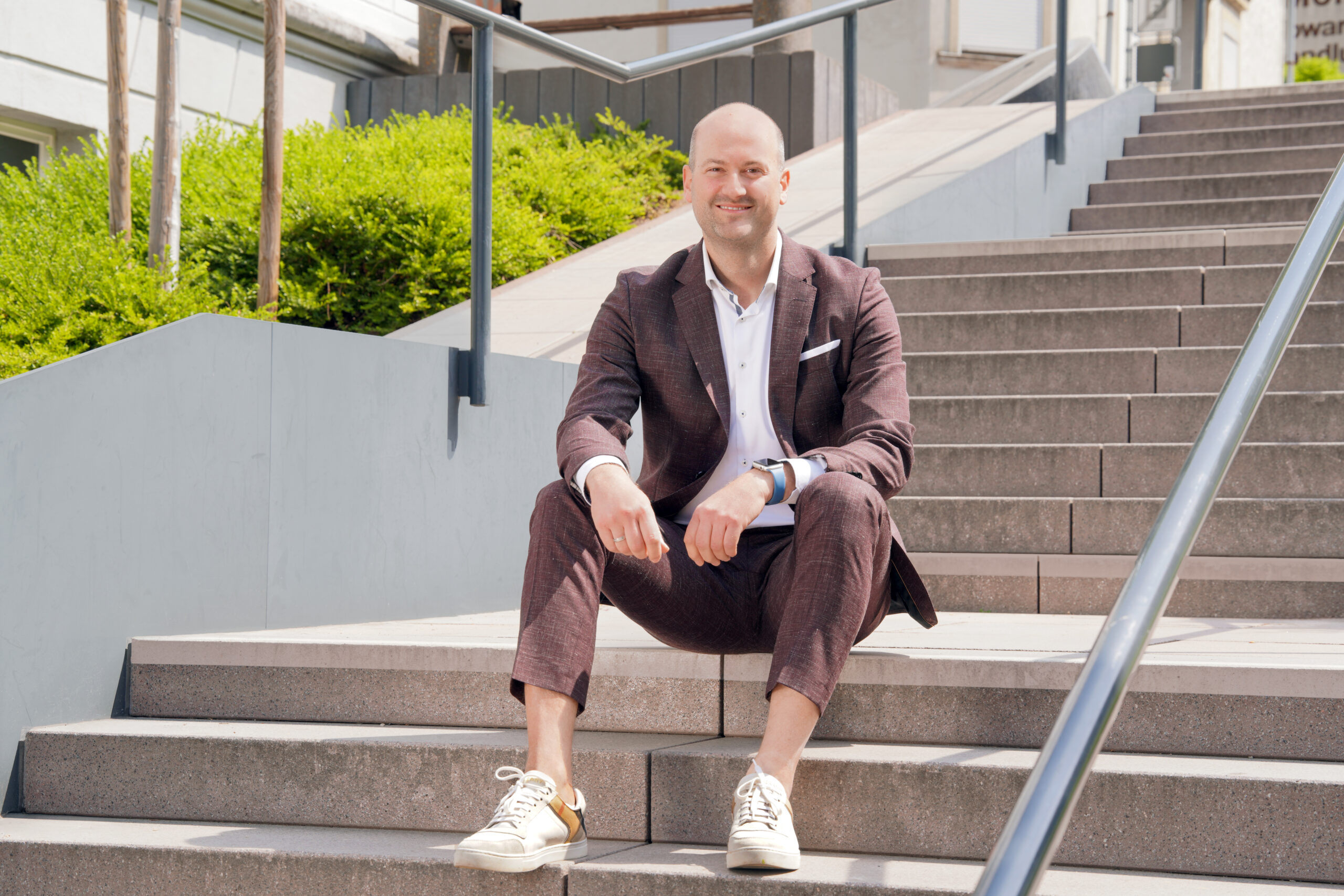 Michael Kranz sitzt locker auf der Treppe vor der Kanzlei