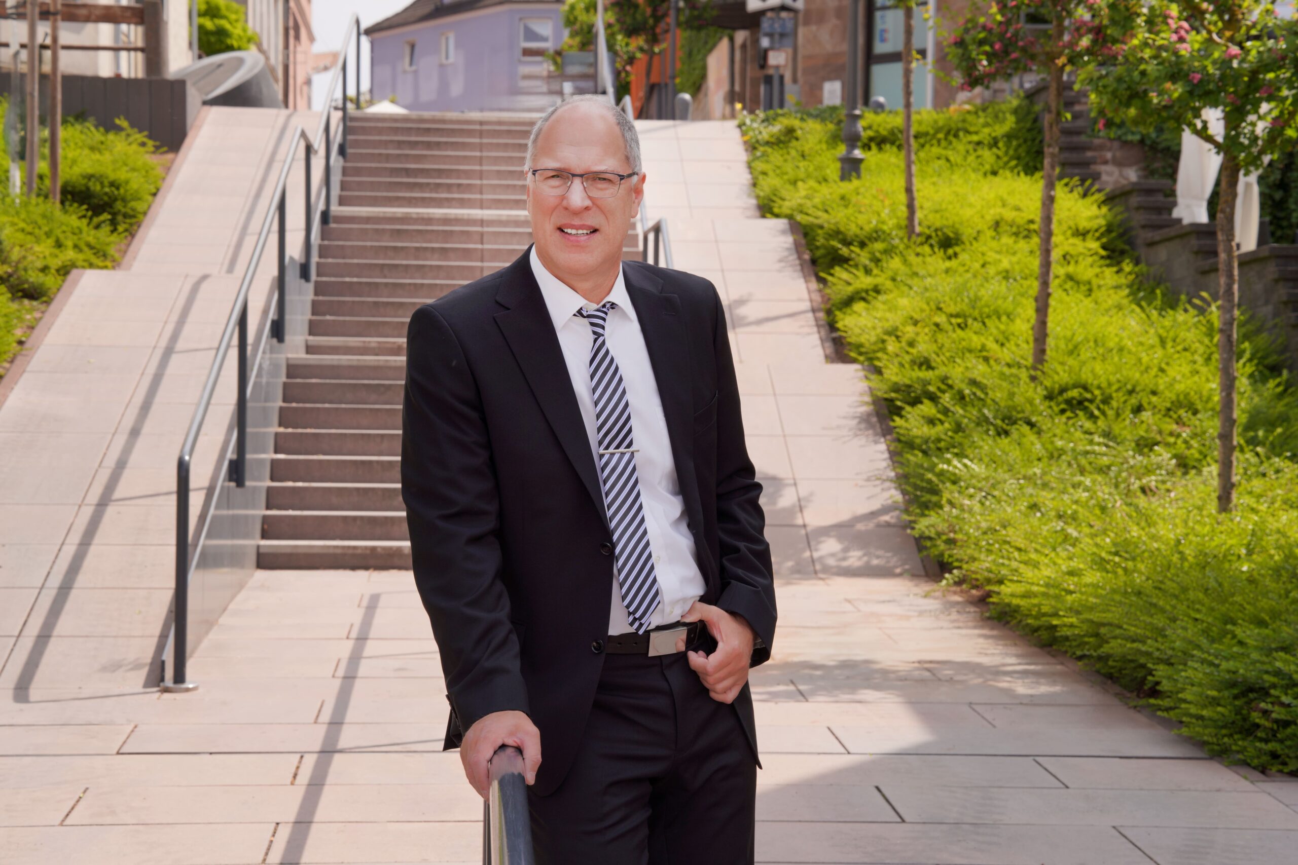 Jürgen Pletsch steht neben der Kanzlei an ein Treppengeländer gelehnt.