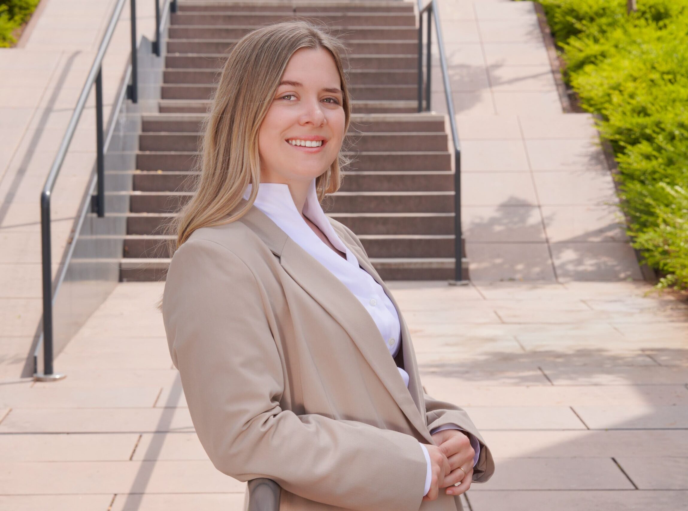 Amelie Hildebrand steht neben der Kanzlei seitlich an ein Treppengeländer gelehnt.