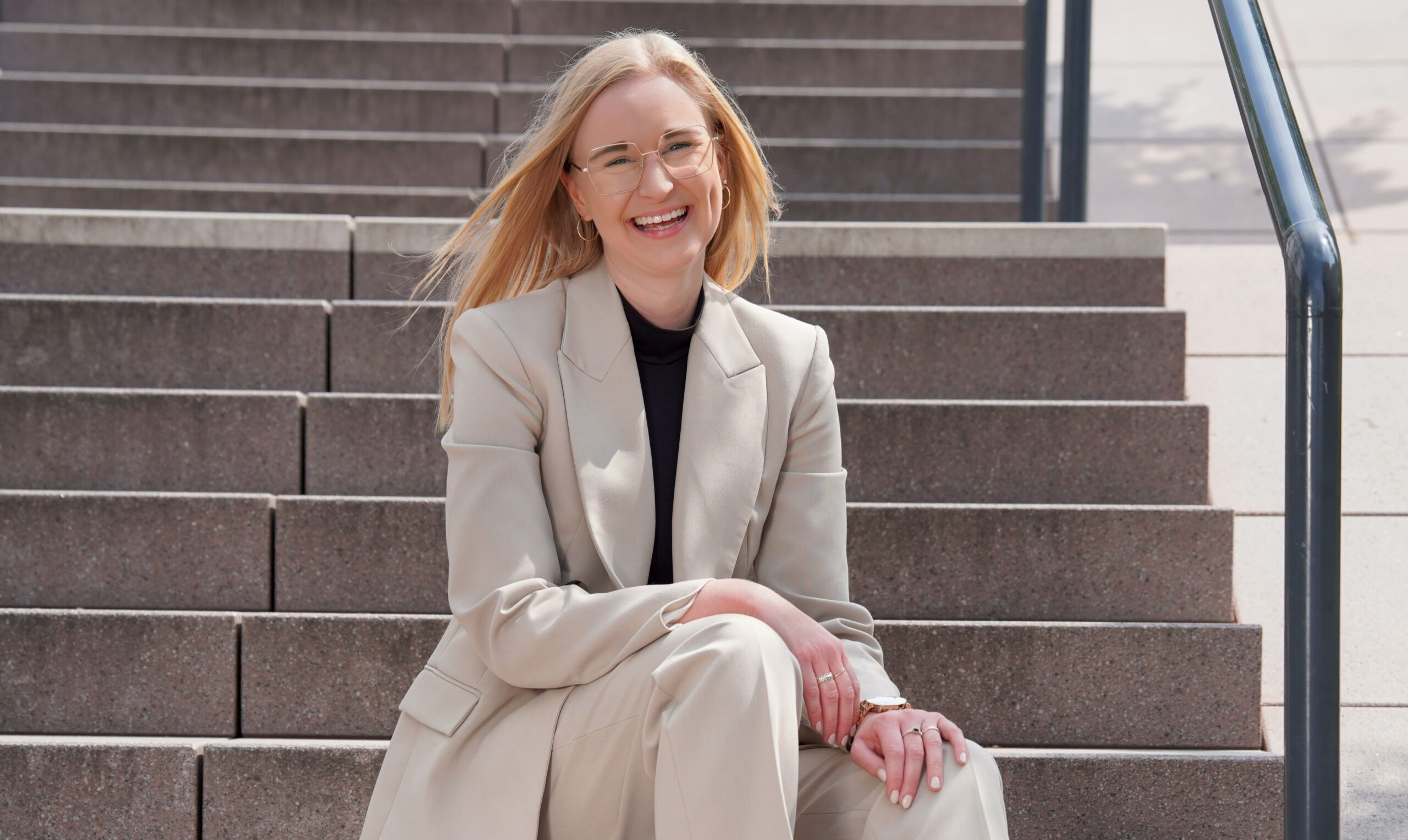 Kim Schneider sitzt lächelnd auf der Treppe von der Kanzlei